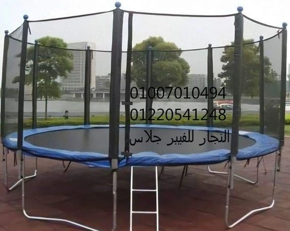 ترامبولين دائري كبير للأطفال مزود بشبكة أمان وحماية زرقاء مع سلم معدني، مثالي لتجهيز مناطق ألعاب أطفال وملاهي خارجية بجانب ألعاب الفيبر جلاس في الحدائق والنوادي.