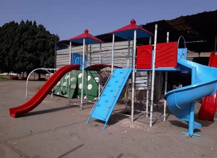 مجمع ألعاب أطفال فيبر جلاس ملون يضم زحاليق فيبر جلاس باللونين الأحمر والأزرق تحت سماء صافية، مع هيكل تسلق وأنفاق فيبر جلاس، مما يوفر تجهيزات ملاهي ممتعة وجذابة للأطفال.