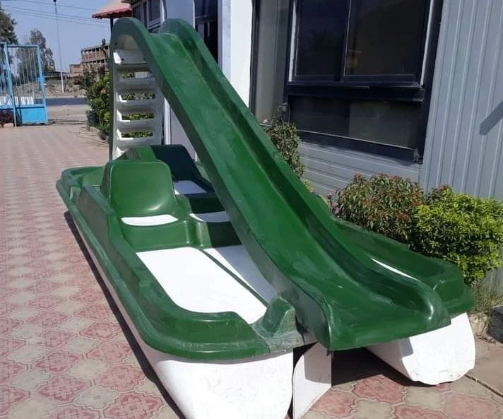 بدال مائي (بدالة) من الفيبر جلاس باللونين الأخضر والأبيض مزود بزحليقة مائية، متوقف بجانب مبنى تحت سماء زرقاء، مثالي لتجهيزات ألعاب مائية فيبر جلاس ومنتزهات البحيرات والأكوا بارك.