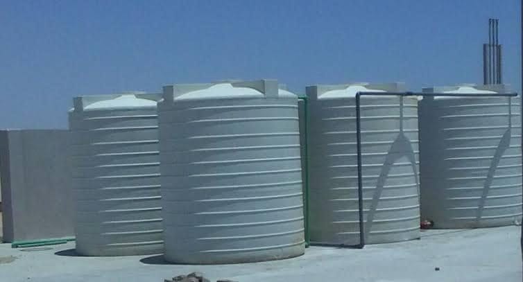 أربعة خزانات مياه فيبر جلاس أسطوانية كبيرة الحجم باللون الأبيض، مثبتة على أرضية خرسانية مستوية تحت سماء صافية، مصنعة من خامات الفيبر جلاس عالية الجودة لتوفير حلول تخزين مياه عملية ومتينة للمشروعات الإنشائية والصناعية.