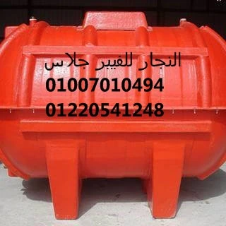 خزان مياه فيبر جلاس كبير باللون الأحمر الزاهي، مطبوع عليه بيانات التواصل والشركة باللغة العربية، موضوع في مستودع صناعي؛ مصنع من خامات الفيبر جلاس عالية الجودة المقاومة للعوامل الجوية والصدأ، ومثالي لتخزين المياه أو المواد الكيماوية في المصانع والمنشآت.