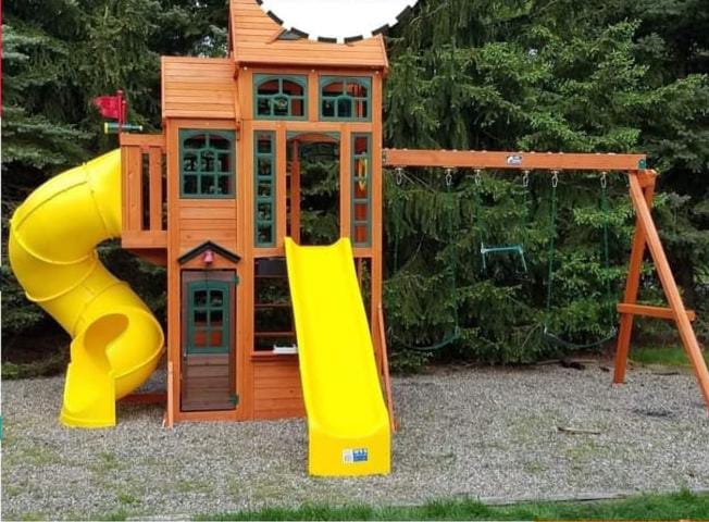 مجمع ألعاب خشبية للحدائق يضم زحليقة فيبر جلاس حلزونية (سبيراي) وزحليقة مستقيمة باللون الأصفر، مع أراجيح متينة وسط مساحات خضراء، مصمم لتوفير أقصى درجات الرفاهية والأمان للأطفال.