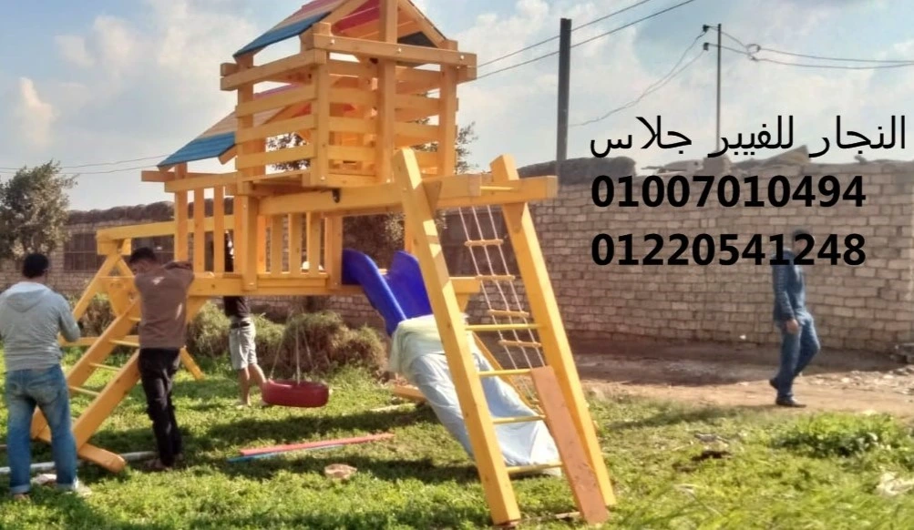 مجمع ألعاب خشبية ملون للحدائق يضم سلالم تسلق، زحليقة فيبر جلاس، وأرجوحة، يتم تركيبه باحترافية على نجيل طبيعي لتوفير منطقة ترفيهية آمنة للأطفال مع أرقام التواصل للتجهيزات في مصر.