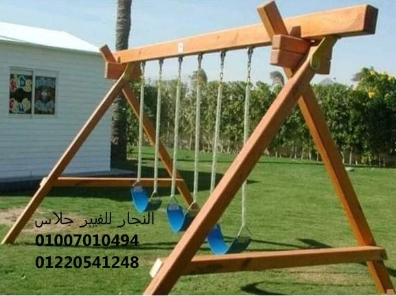 أرجوحة خشبية للحدائق تضم ثلاثة مقاعد أراجيح فيبر جلاس متينة باللون الأزرق، مثبتة بانتظام على نجيل أخضر لتوفير منطقة ترفيهية آمنة ومقاومة للعوامل الجوية مع أرقام التواصل للتجهيزات.